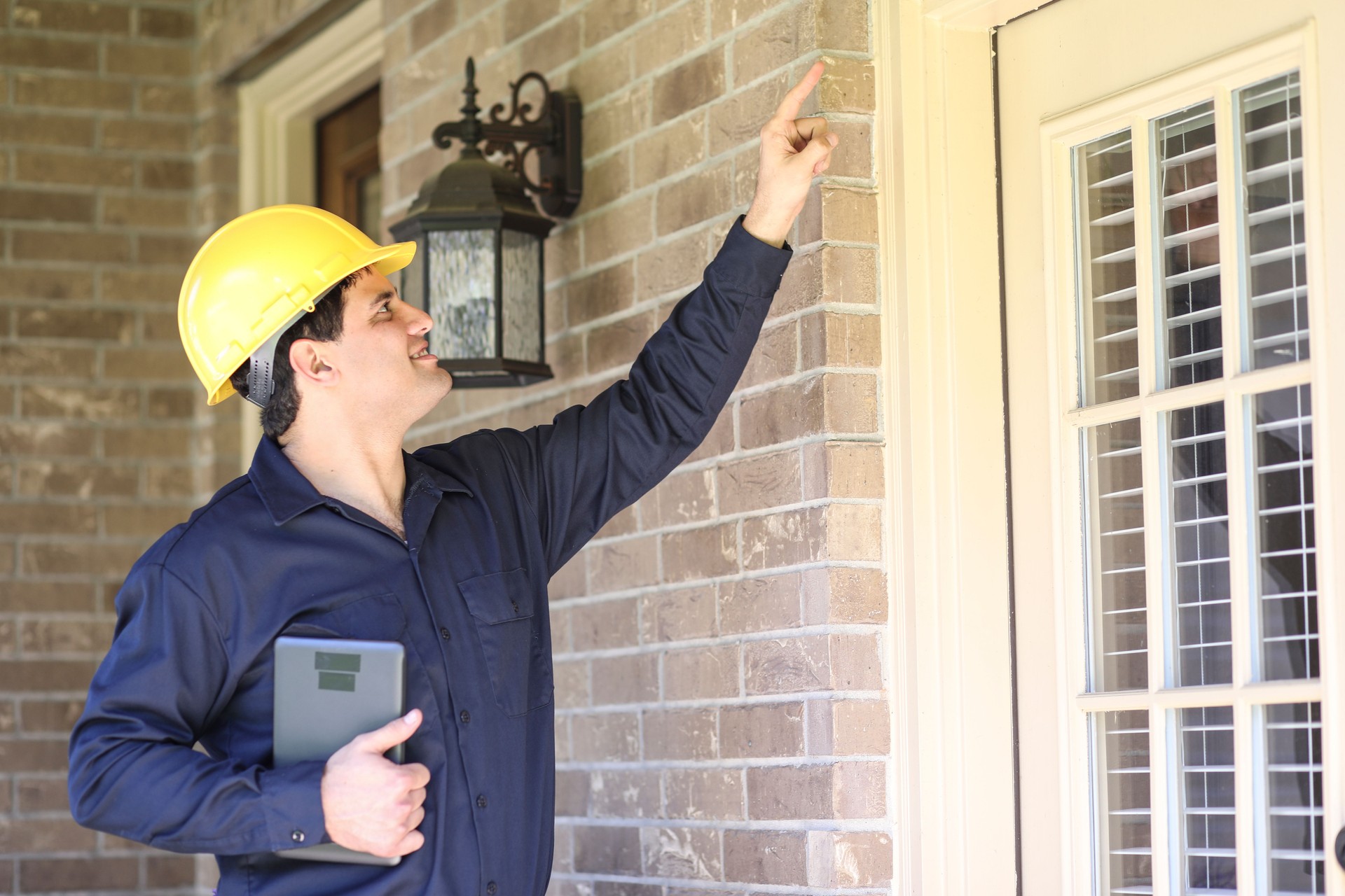 Latin descent man inspects home exterior. Contractor, inspector.